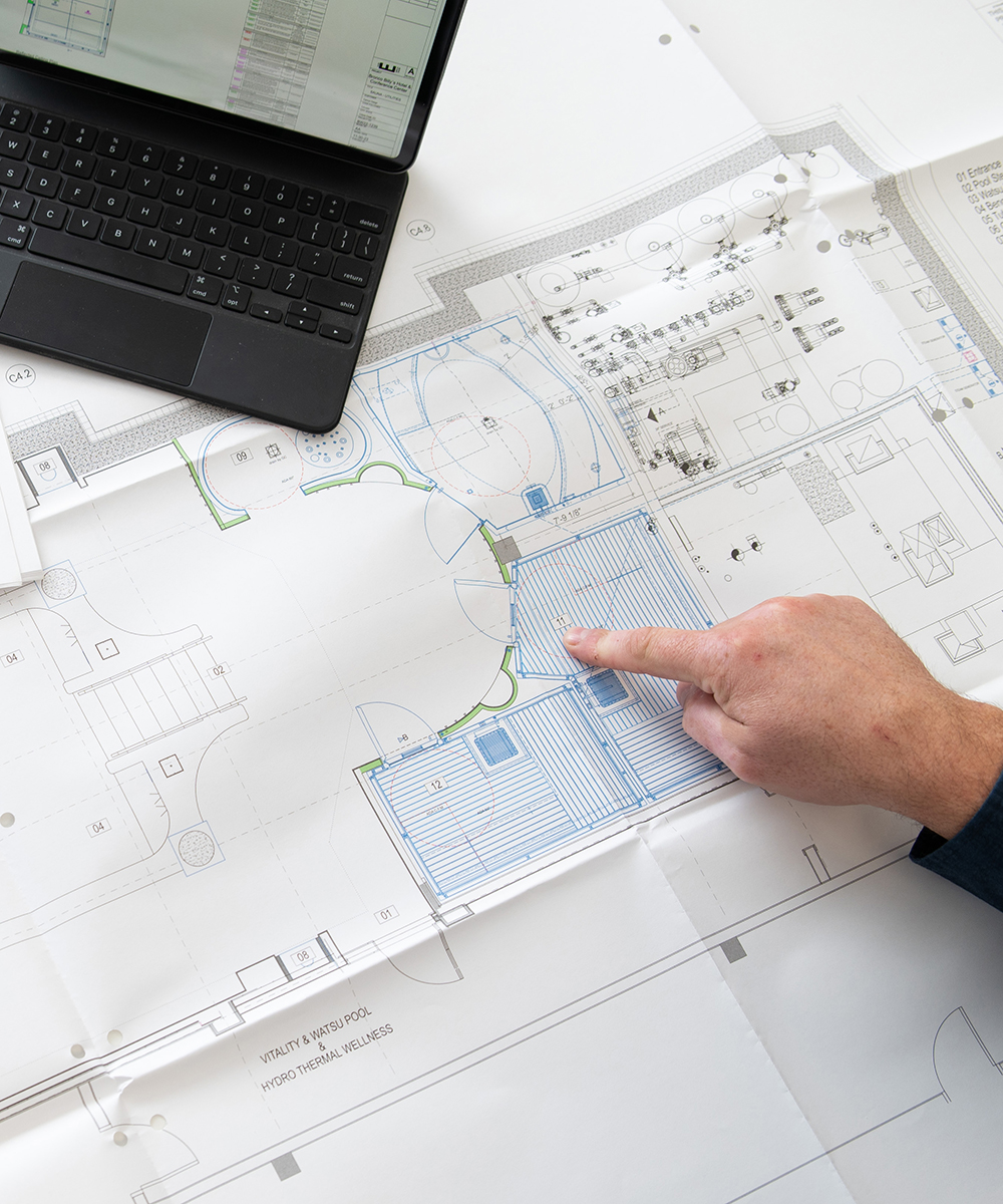 hand pointing at spa engineering drawings